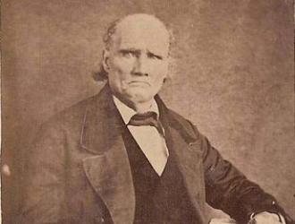 Sepia portrait photograph of Morgan Walker, and elderly man, seated with a coat and tie